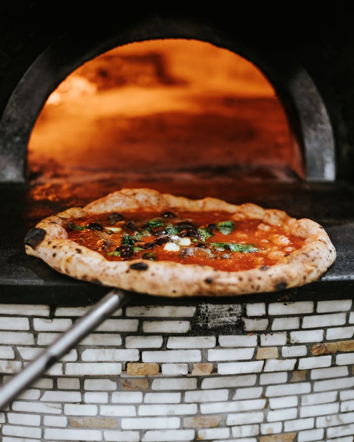 Freshly baked Neapolitan pizza emerging from a wood-fired oven in Naples.